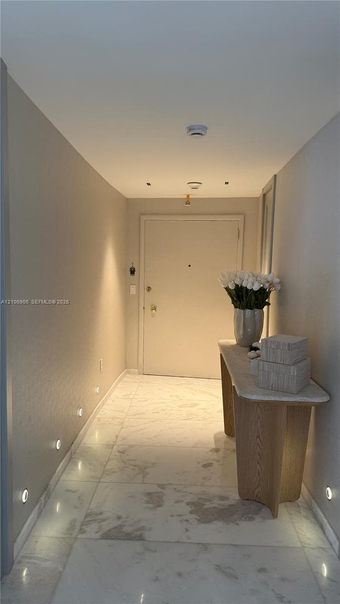 Entrance featuring large-format light-toned stone-finish flooring and integrated low-profile wall lighting