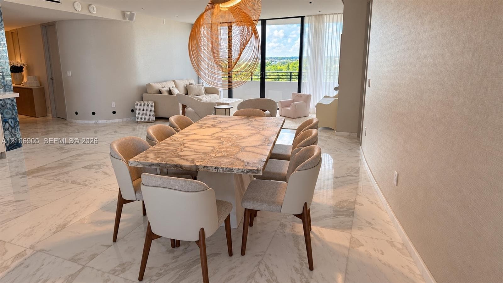 Polished stone flooring, floor-to-ceiling windows, curved architectural wall, and modern hanging light fixture