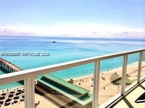 Balcony with glass panel railing overlooking the ocean and sandy coastline