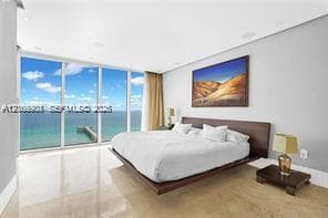 Floor-to-ceiling glass panel walls, light-toned stone flooring, and recessed ceiling lighting