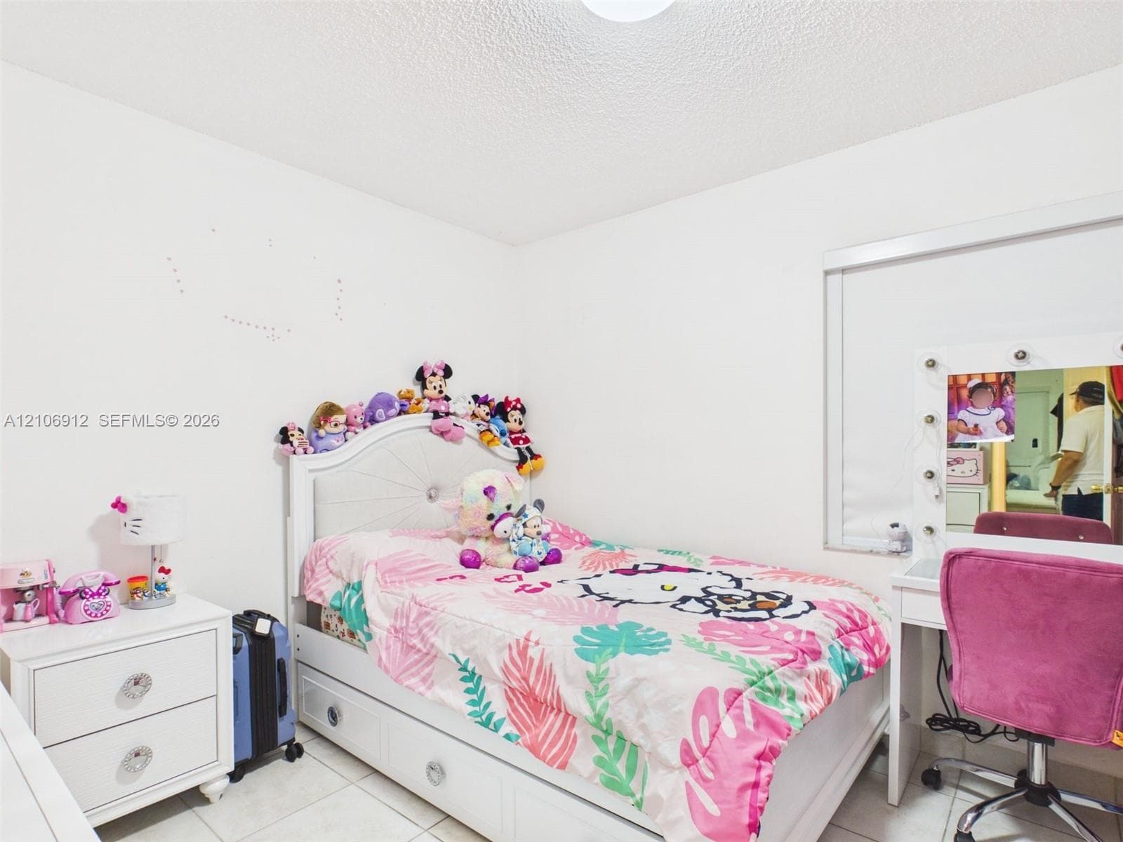 Room featuring white walls, large-format tile flooring, and a window equipped with an integrated roller shade
