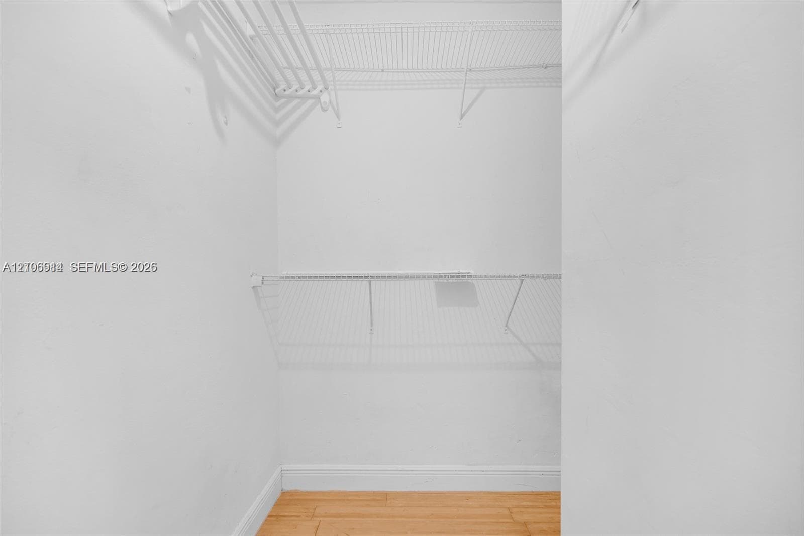 Storage closet featuring wood-finish flooring and dual-level white wire shelving