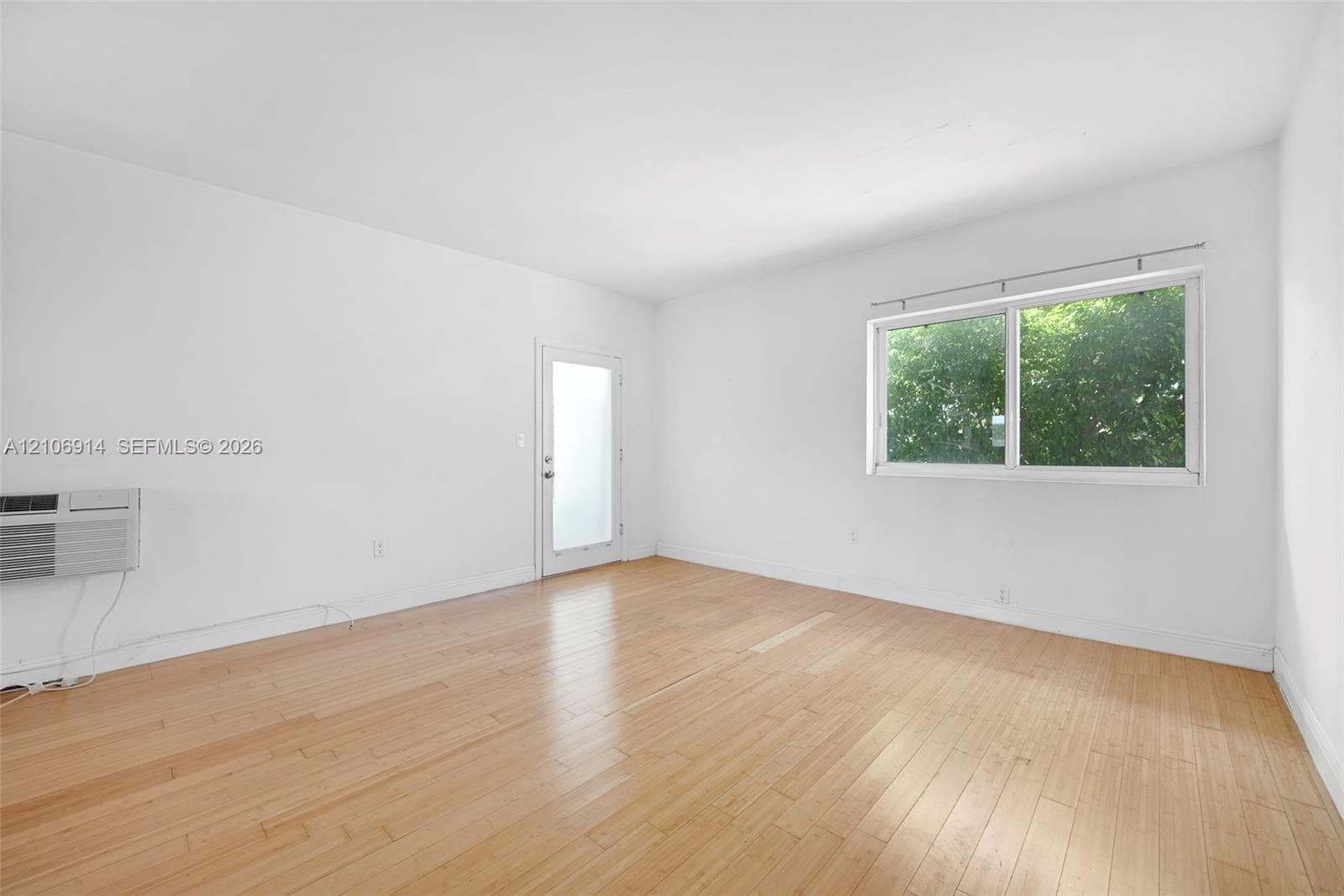 Room featuring wood-finish flooring, a single-pane horizontal sliding window, and a glass-panel exterior door