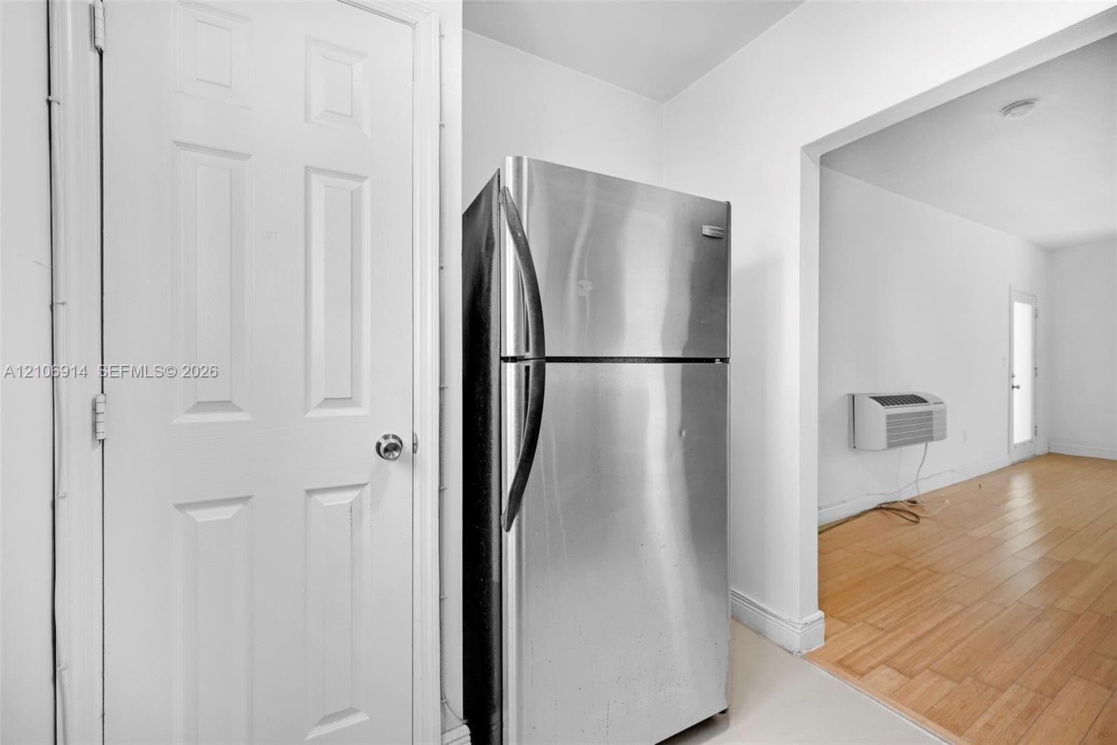 Stainless steel refrigerator, wood-finish flooring, and six-panel interior door