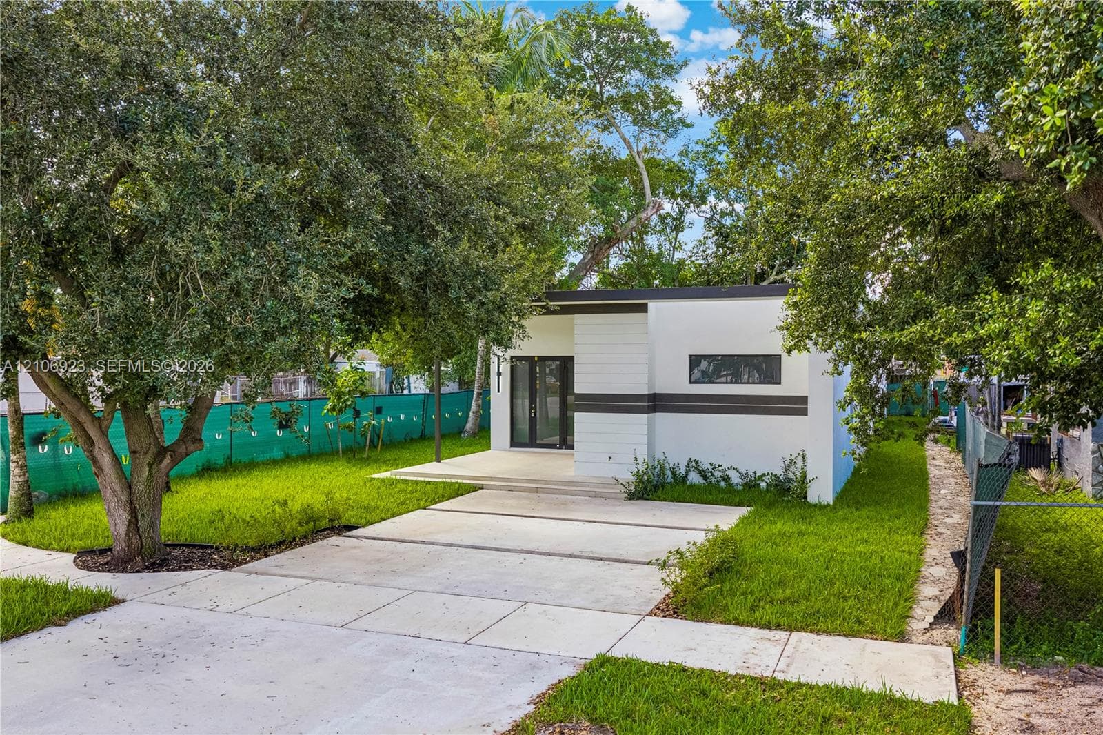 Modern minimalist exterior featuring a crisp white finish with linear accent detailing, concrete driveway, and a covered entry
