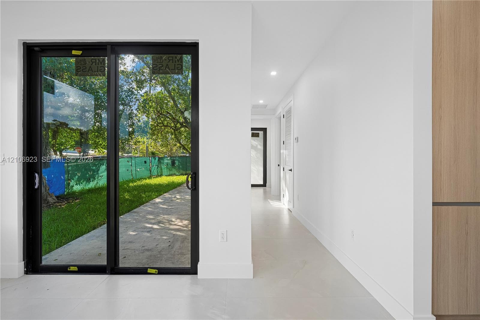 Black-framed sliding glass doors, neutral tile flooring, recessed ceiling lighting, and wood-finish cabinetry
