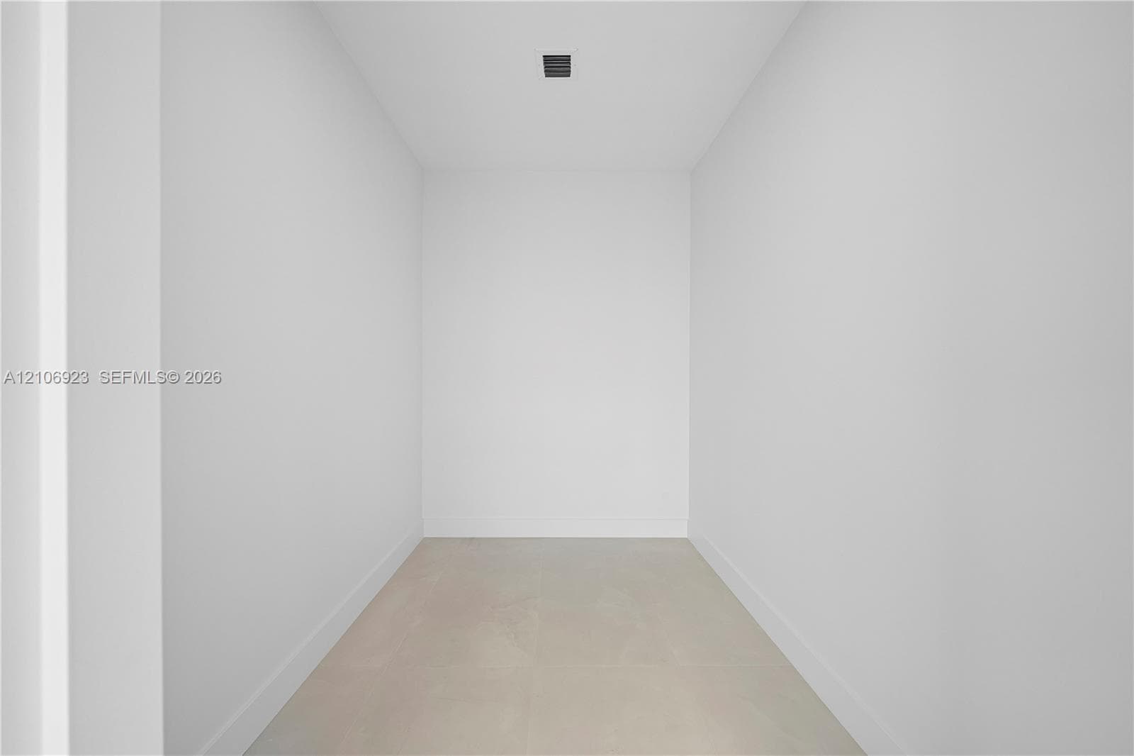 Minimalist interior space featuring neutral wall tones, large-format tile flooring, and recessed ceiling lighting