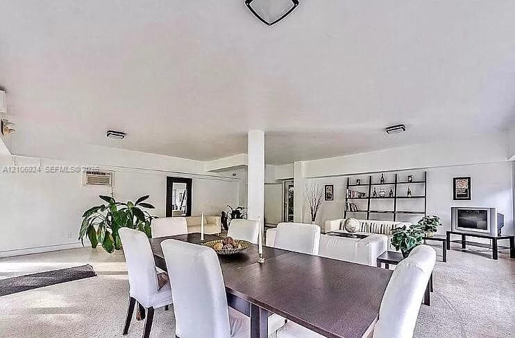 Open-concept interior featuring wall-to-wall carpeting, neutral white walls, a central structural column, and built-in metal shelving