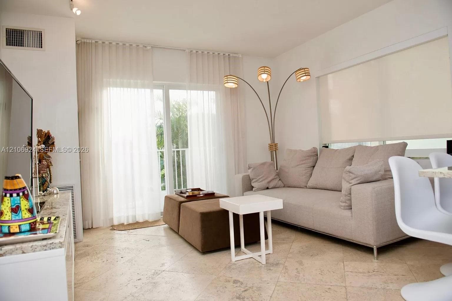 Stone-tile flooring and glass sliding doors with sheer drapery