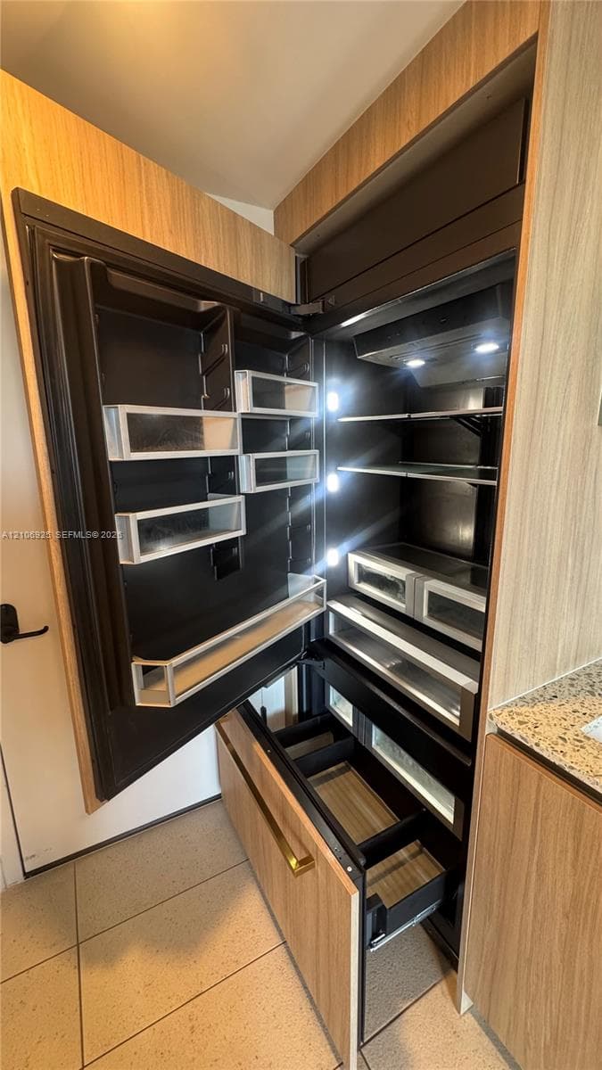 Floating vanity with a light wood-finish cabinet, stone-composite countertop, rectangular vessel sink, wall-mounted backlit mirror, and metallic finish plumbing fixtures