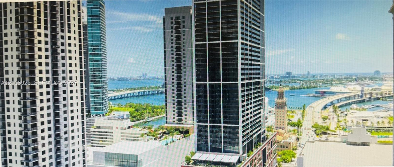 Covered balcony with a glass and metal railing featuring panoramic urban and waterfront scenery