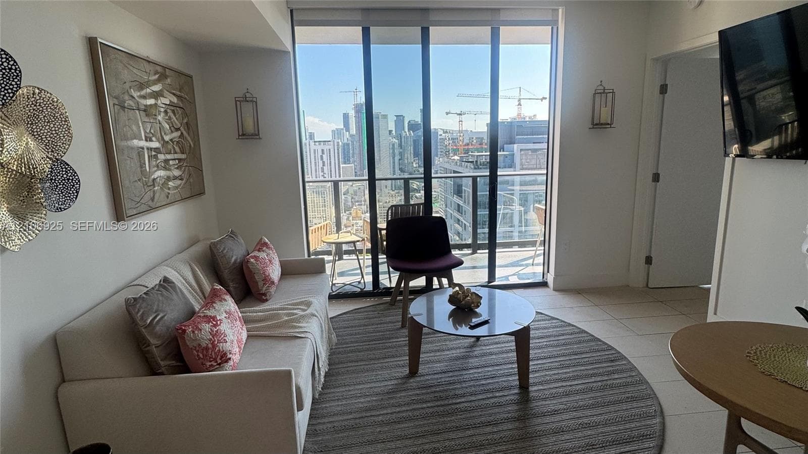 Floor-to-ceiling windows, porcelain tile flooring, modern multi-arm light fixture, and an attached balcony