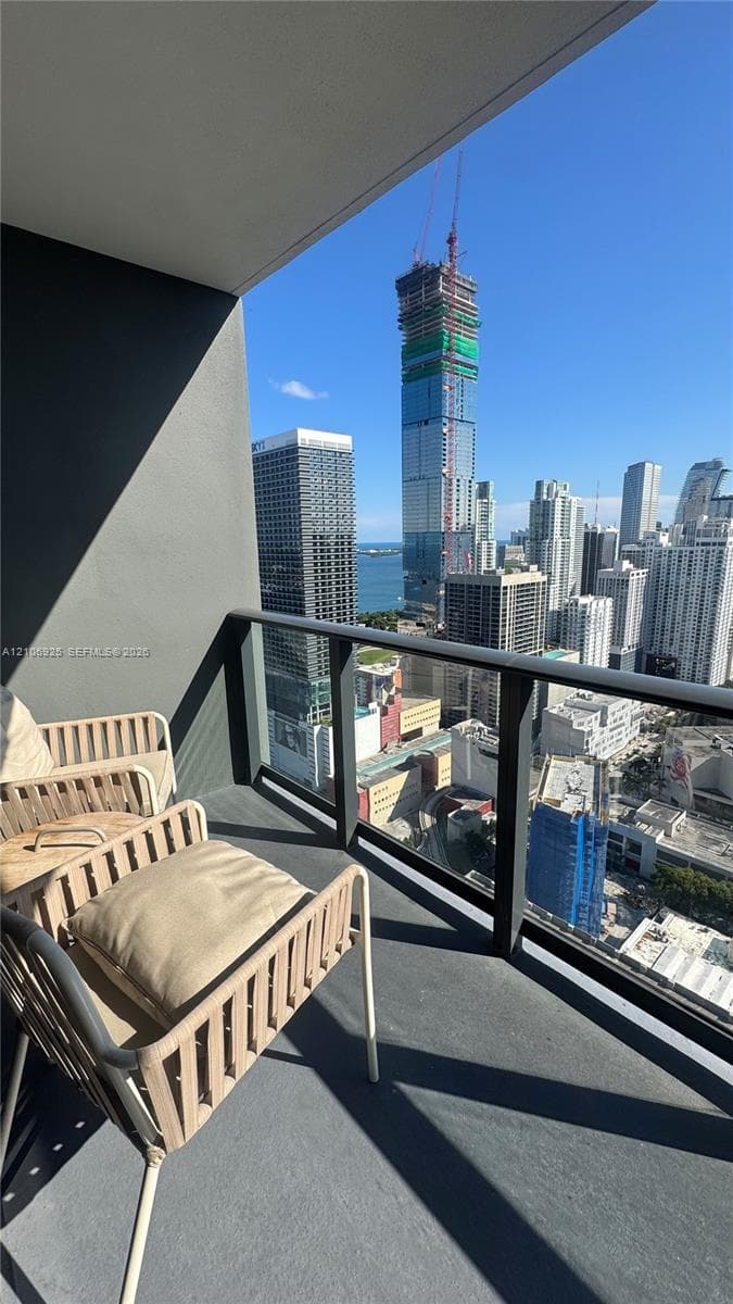 Covered balcony featuring a sleek glass railing and panoramic urban skyline scenery
