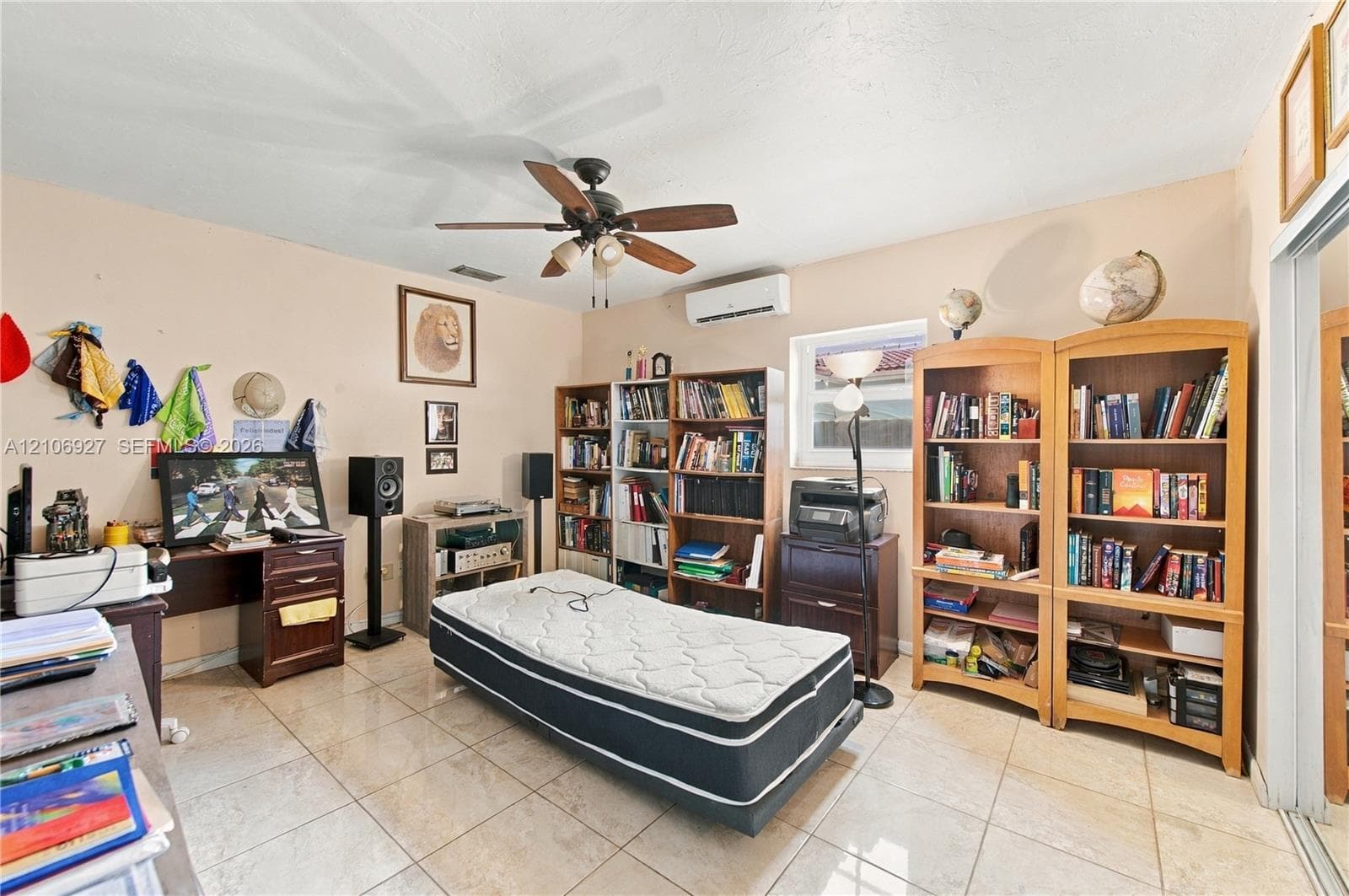 Room featuring neutral wall paint, polished tile flooring, ceiling fan with integrated lighting, and a wall-mounted ductless air conditioning unit
