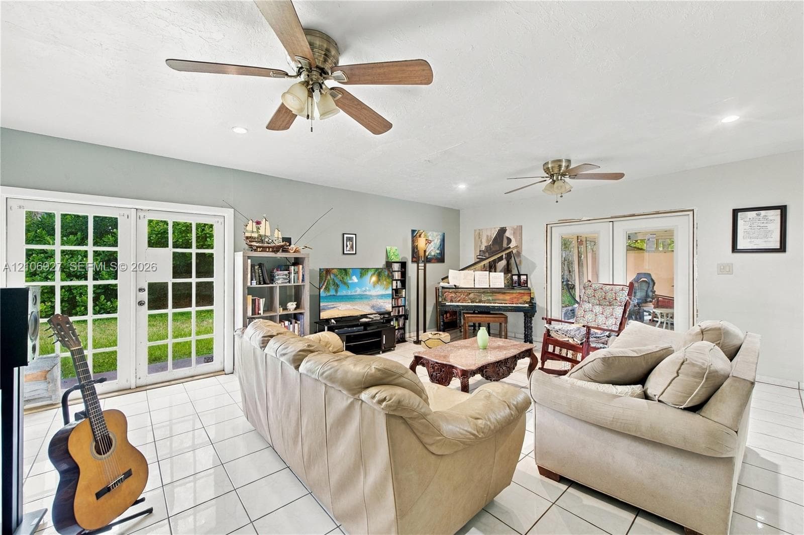 Spacious interior featuring white ceramic tile flooring, dual ceiling fans, and two sets of double-paned French doors