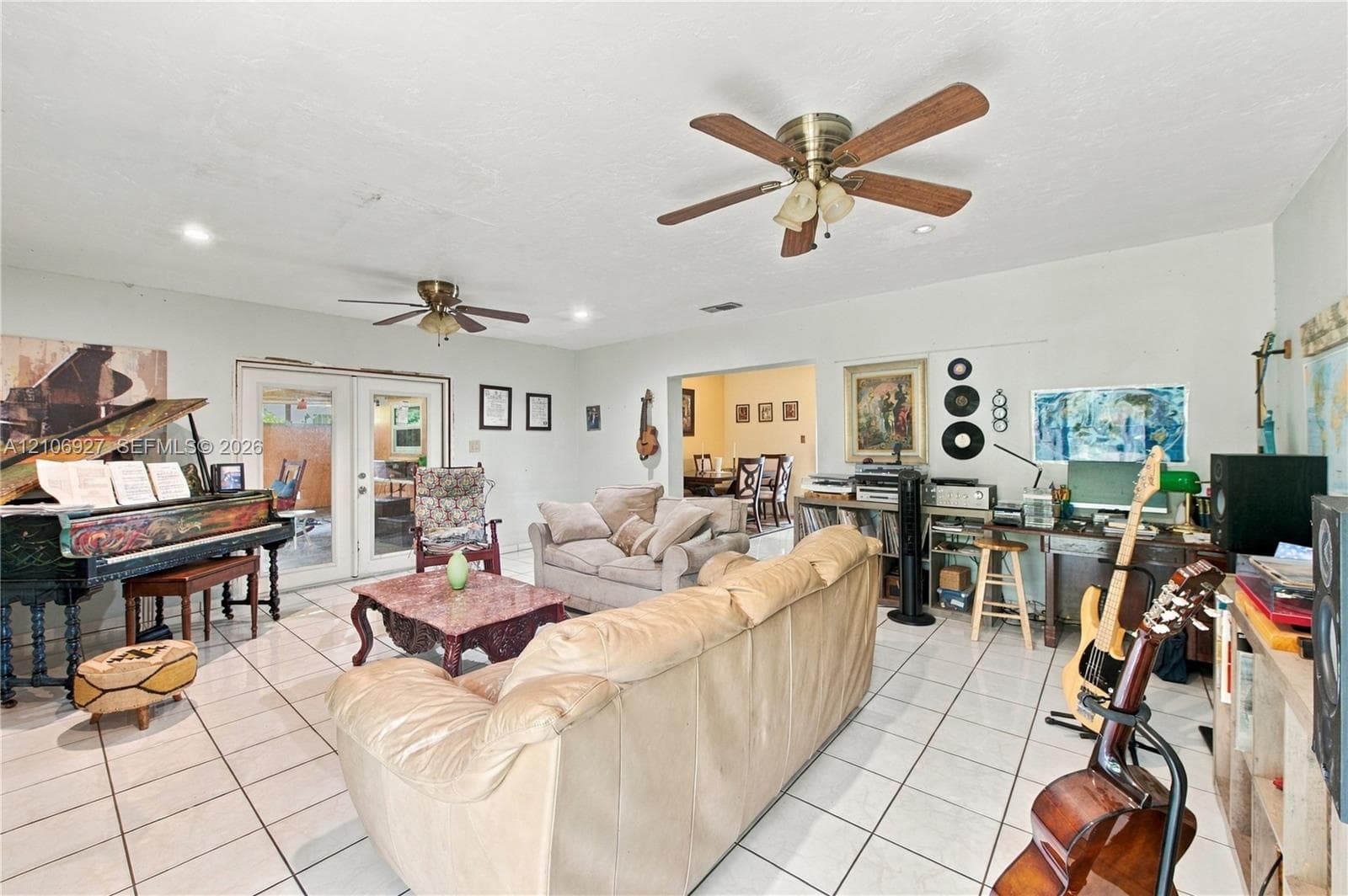 Spacious room featuring tile flooring, dual ceiling fans, and French doors