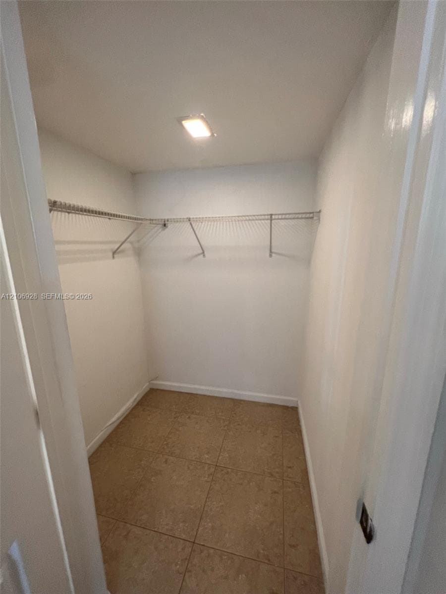 Walk-in storage space featuring ceramic tile flooring, neutral walls, and integrated wire shelving
