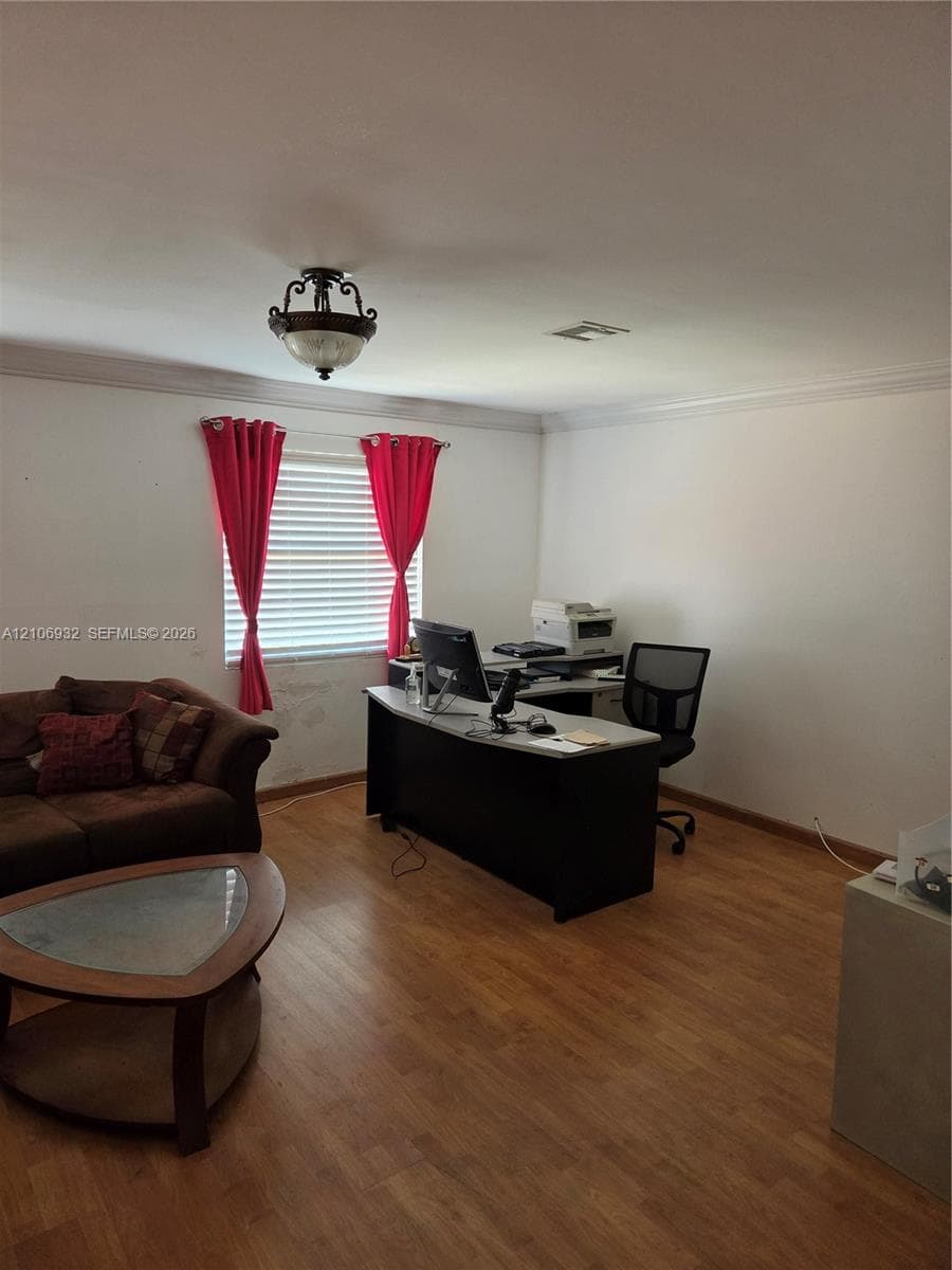 Wood-finish flooring, crown molding, and a semi-flush mount light fixture