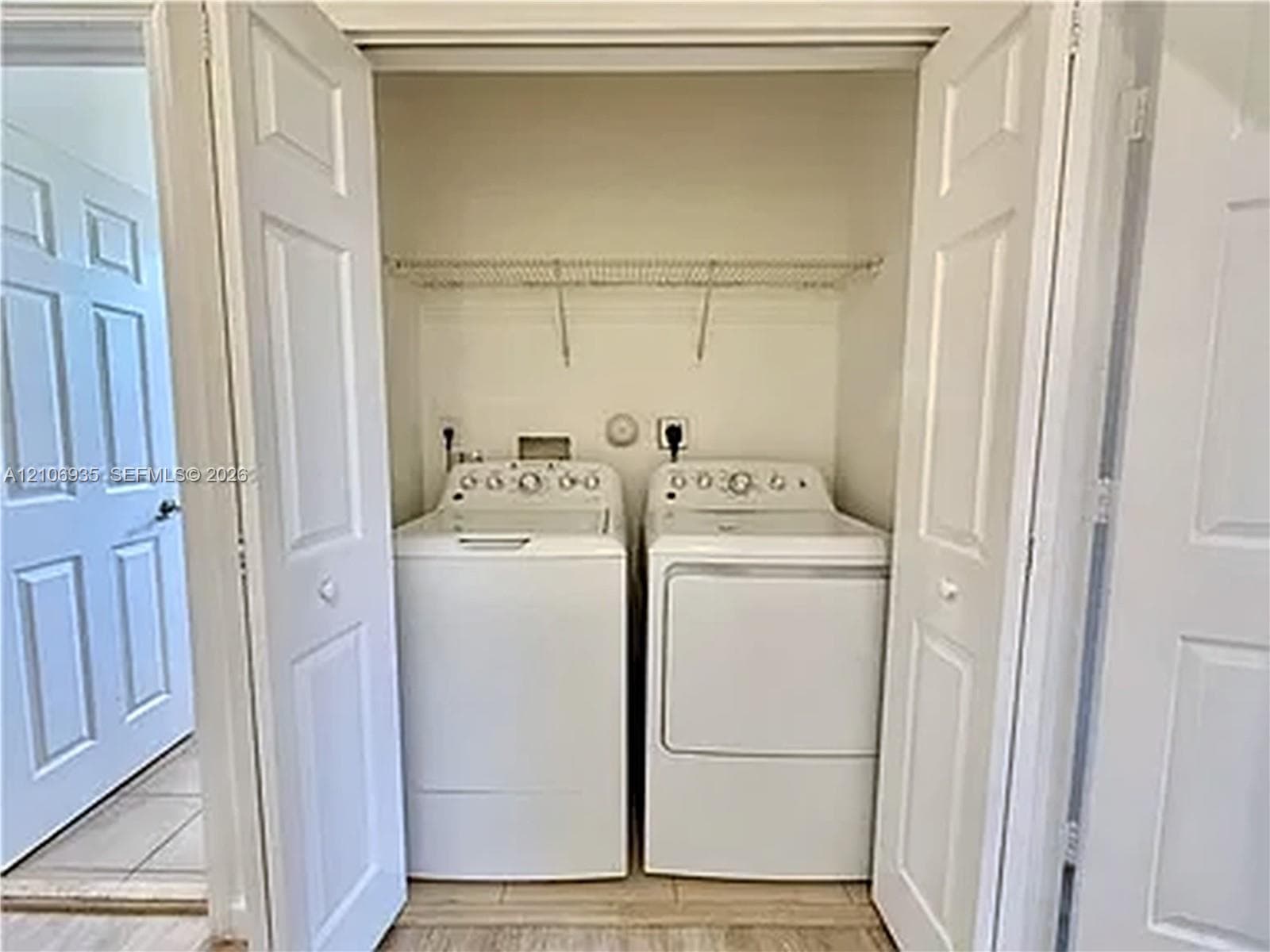 Laundry closet featuring a wire shelving rack, dual-panel folding doors, and neutral tile flooring