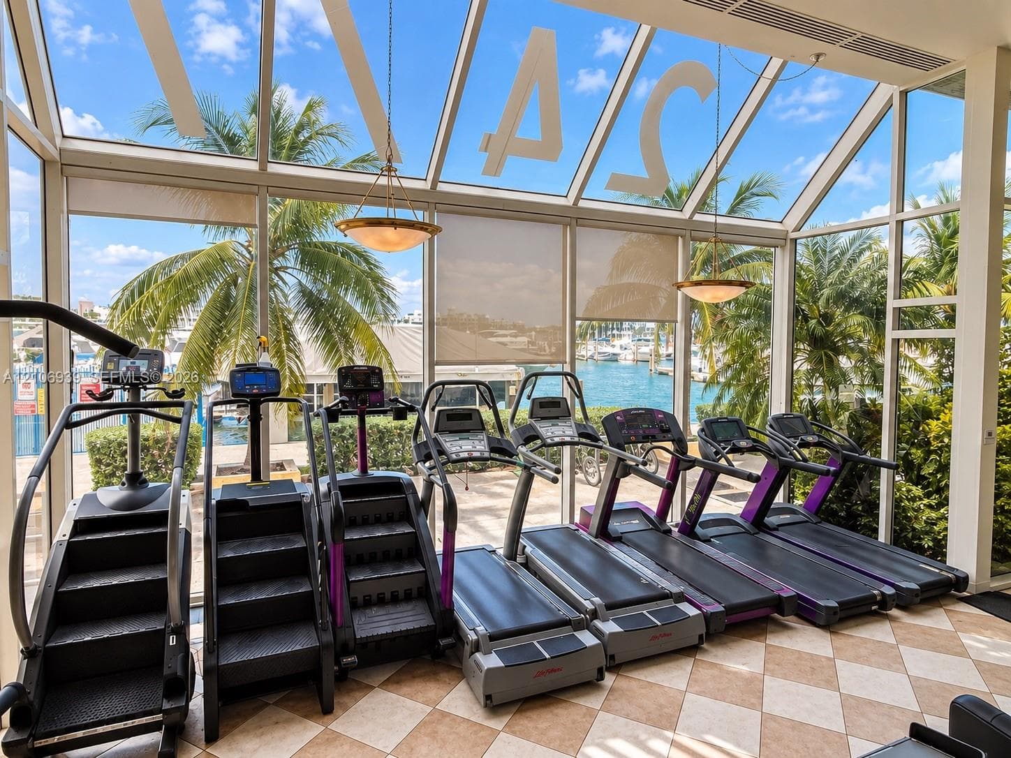 Fitness room featuring floor-to-ceiling glass walls, a vaulted glass ceiling, stone tile flooring, and two suspended pendant light fixtures