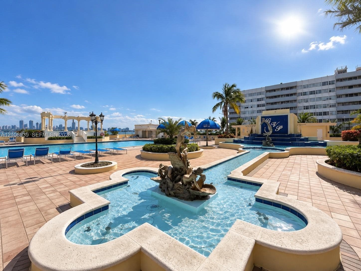 In-ground swimming pool with stone-tiled decking, decorative central fountain feature, built-in water feature with tiled backdrop, and stone pergola structure