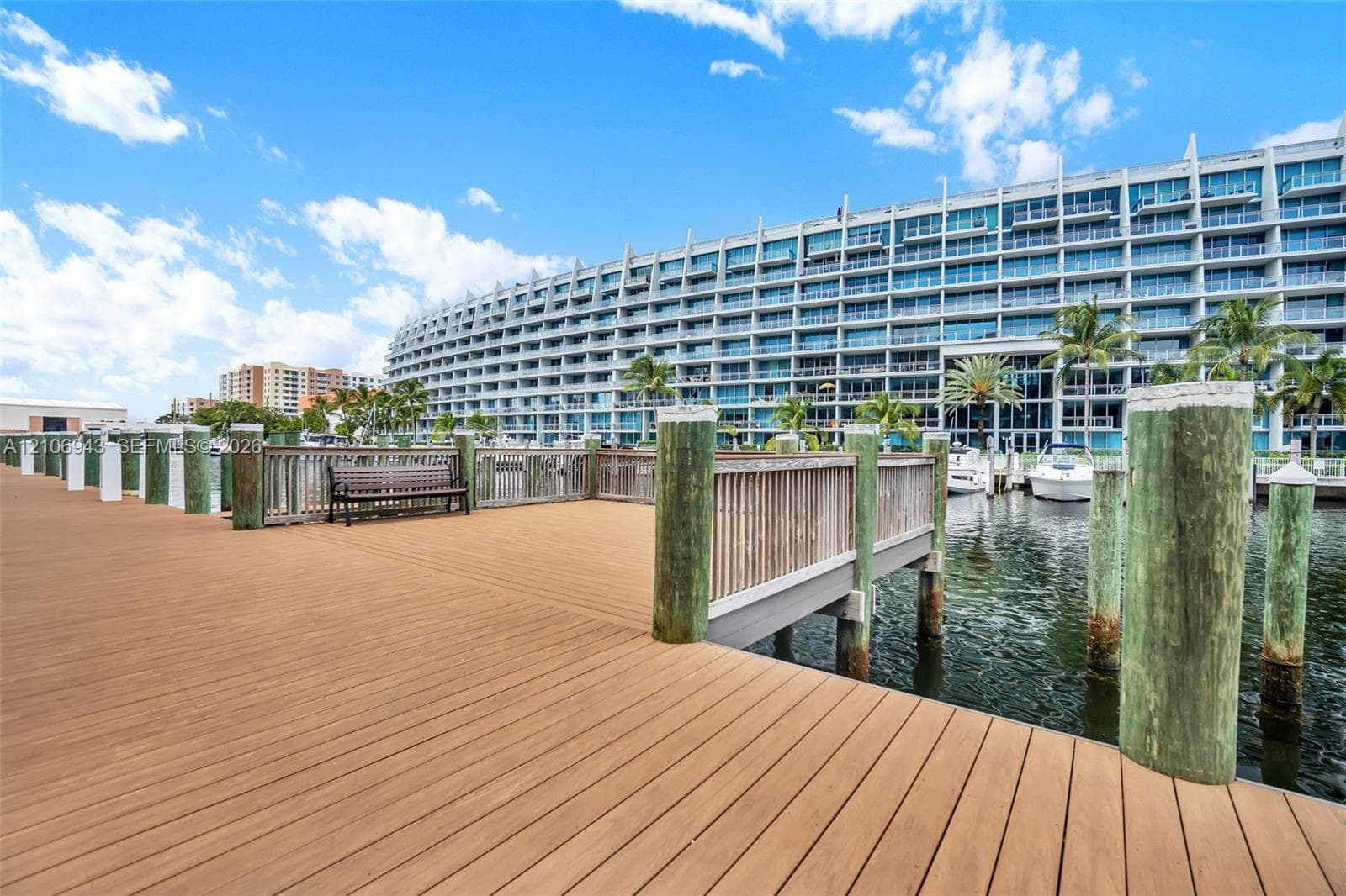 Waterfront wooden dock featuring composite decking, integrated wood-slatted railing, and structural pilings