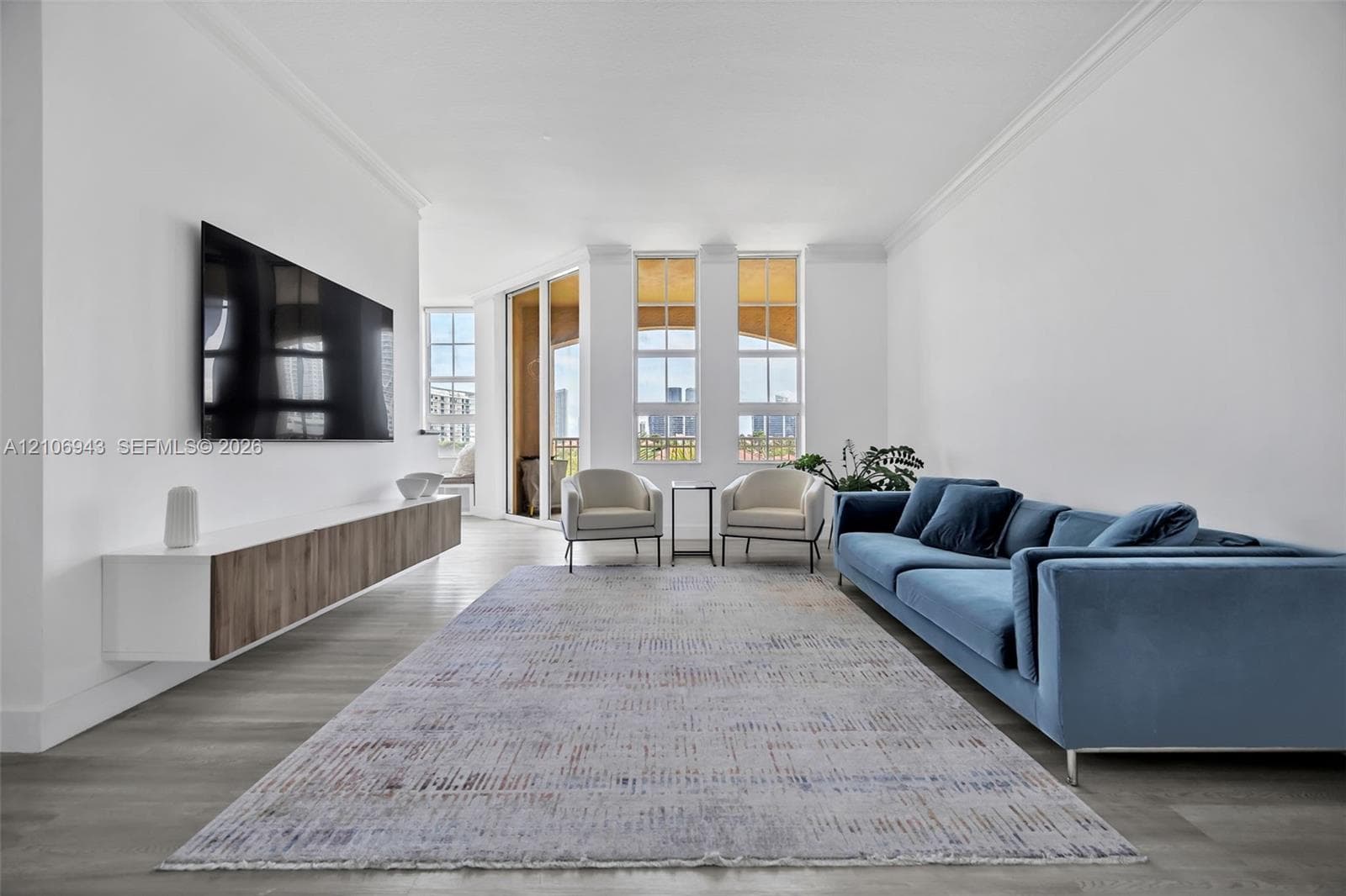 Living area featuring wood-finish flooring, crown molding, a wall-mounted floating cabinet with wood-finish cabinetry, and floor-to-ceiling windows