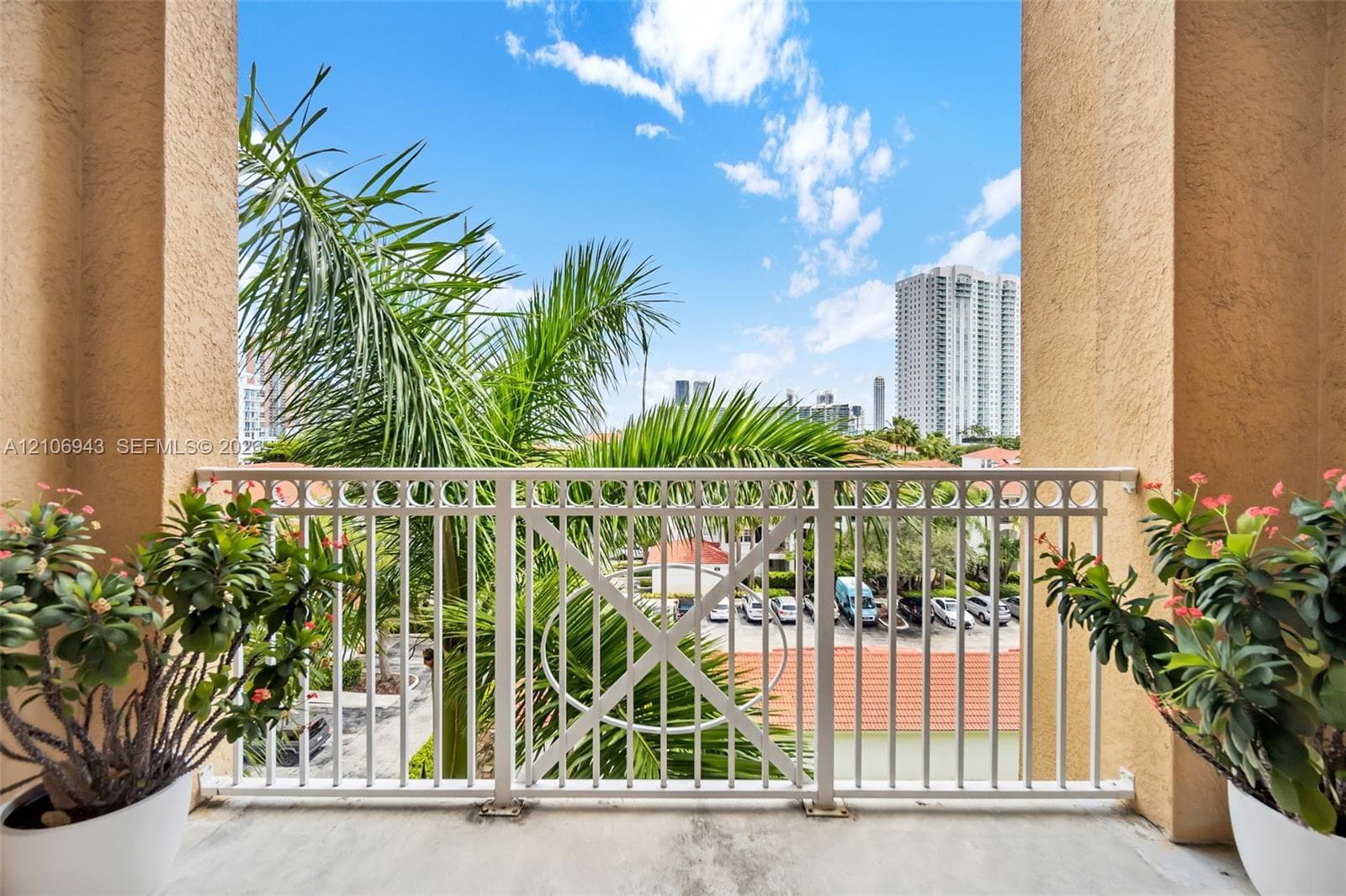 Covered balcony featuring concrete flooring, textured stucco columns, and a white metal geometric railing
