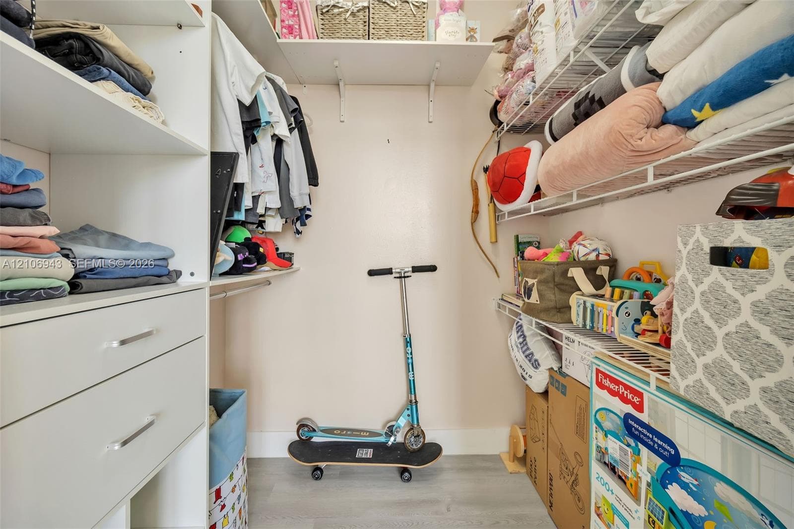 Walk-in closet featuring white built-in shelving, integrated storage drawers, and wire rack shelving systems