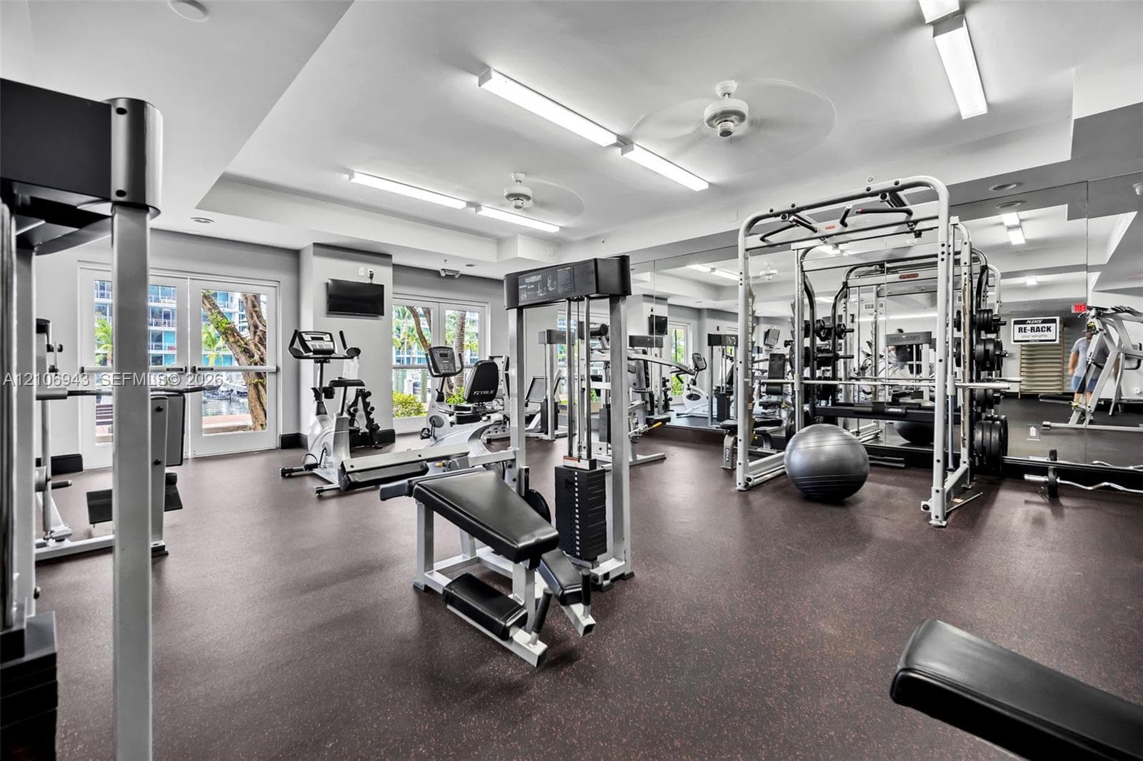 Fitness center featuring rubber flooring, mirrored walls, recessed lighting, and dual ceiling fans