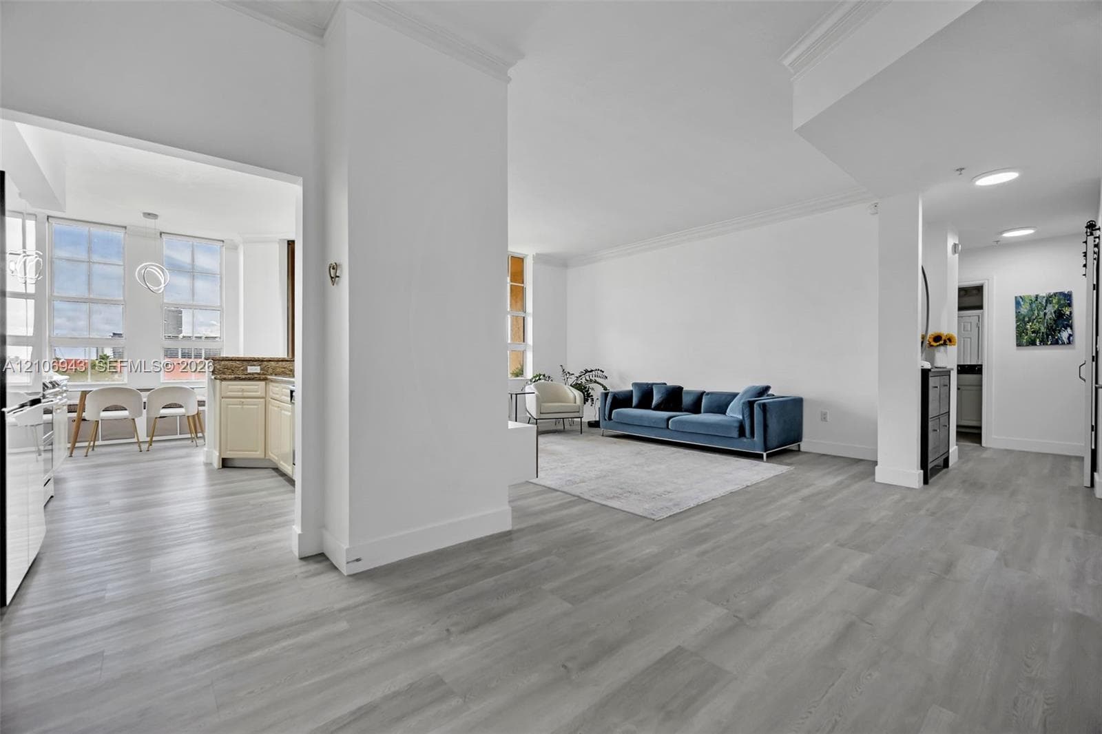Open-concept interior featuring wood-finish flooring, crown molding, recessed lighting, and multi-pane windows