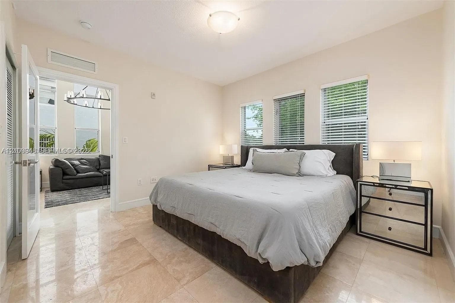 Neutral-toned room featuring large-format polished stone flooring, three windows with horizontal blinds, and a semi-flush mount ceiling fixture