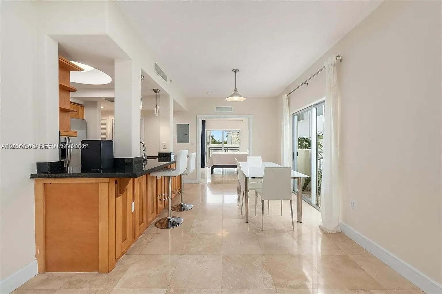 Kitchen featuring natural wood cabinetry, dark stone countertops, stone tile flooring, and integrated pendant lighting