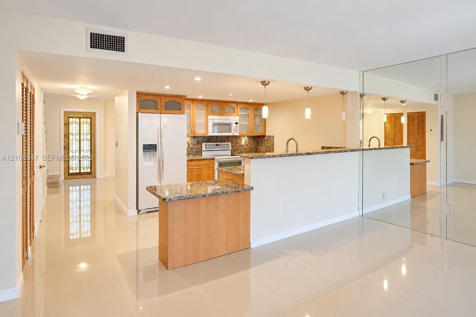Kitchen featuring wood cabinetry, stone countertops, a breakfast bar, recessed lighting, and tile flooring