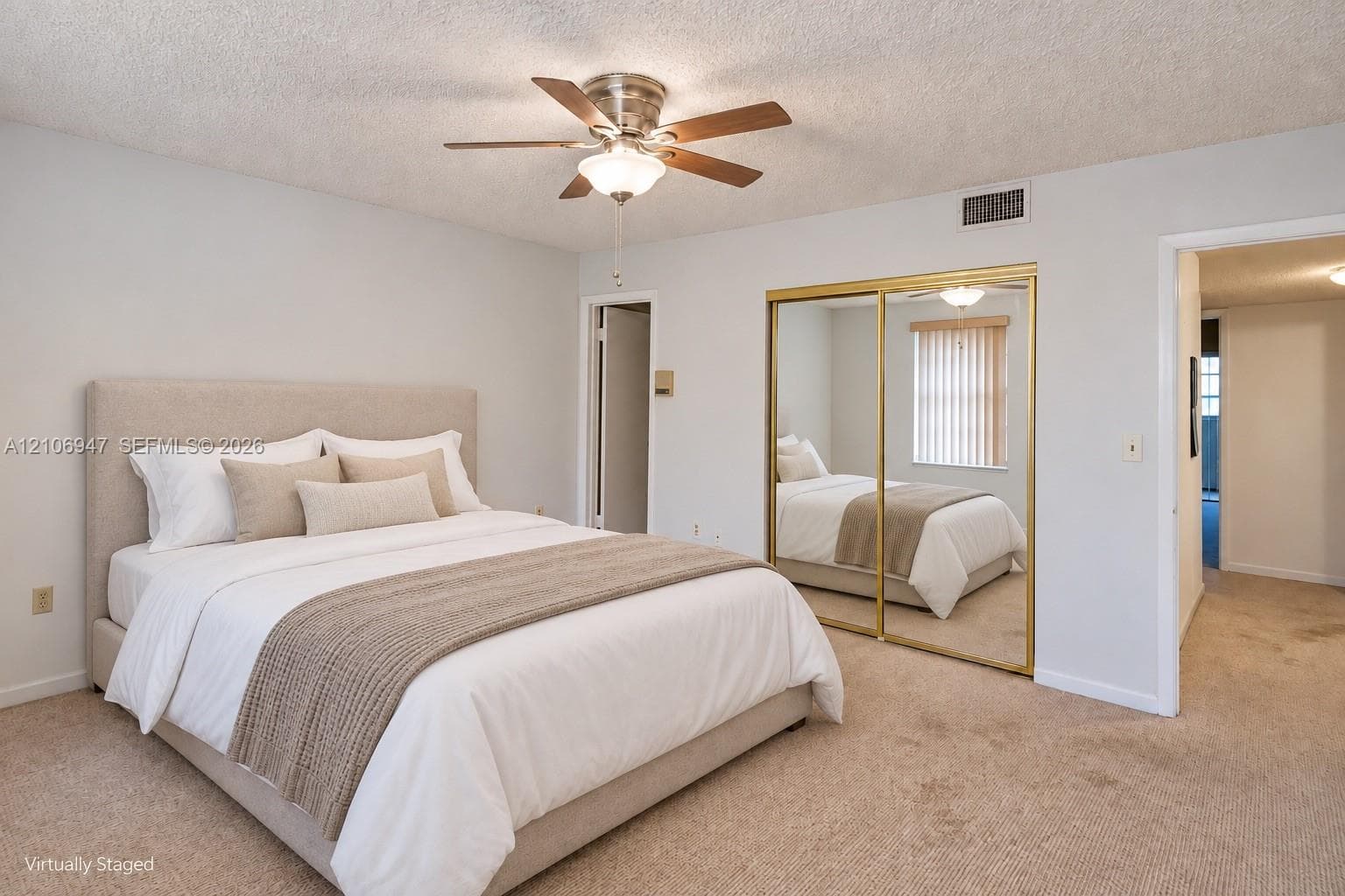 Neutral-toned room featuring a ceiling fan with integrated lighting and sliding bypass closet doors with gold-tone metal framing