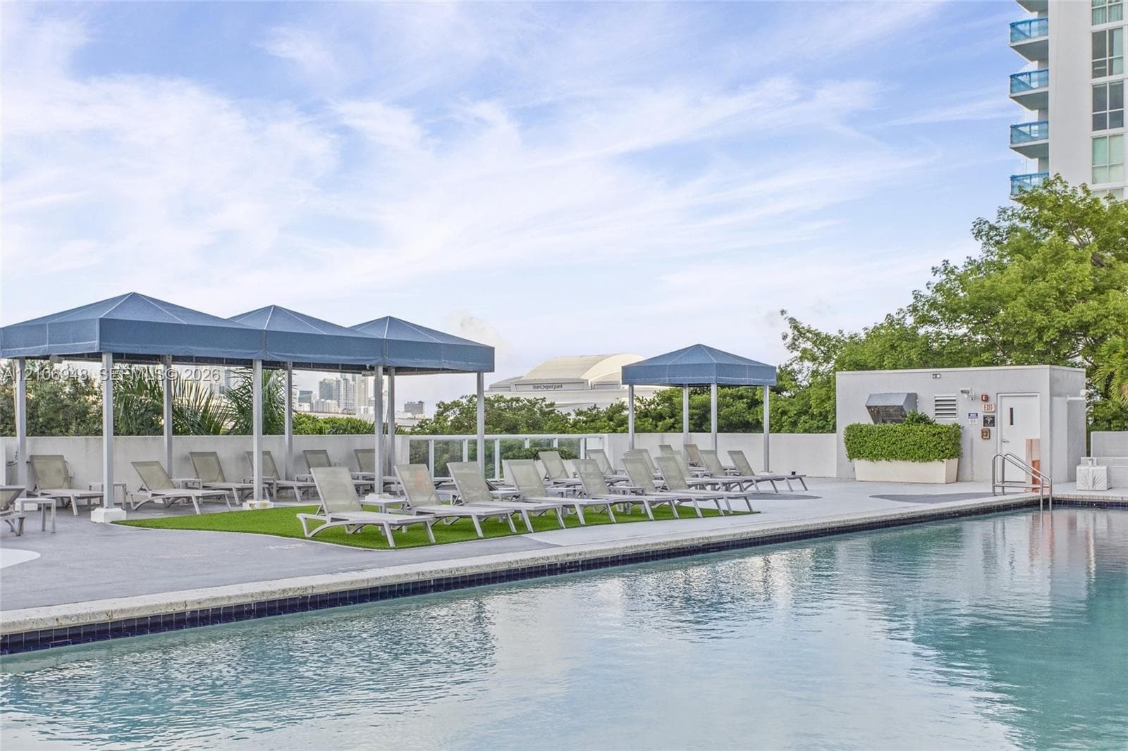 Rooftop swimming pool featuring a concrete deck, glass panel railings, and multiple shaded cabanas