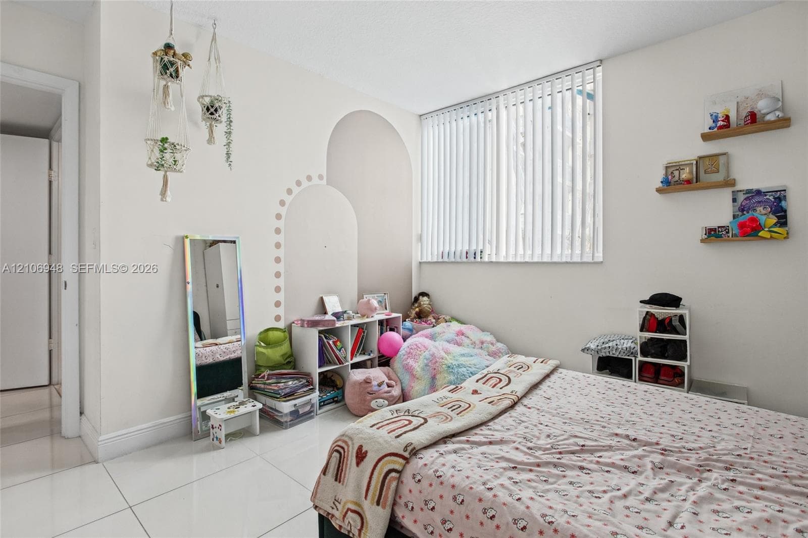 Room featuring large-format white tile flooring and floor-to-ceiling vertical blinds