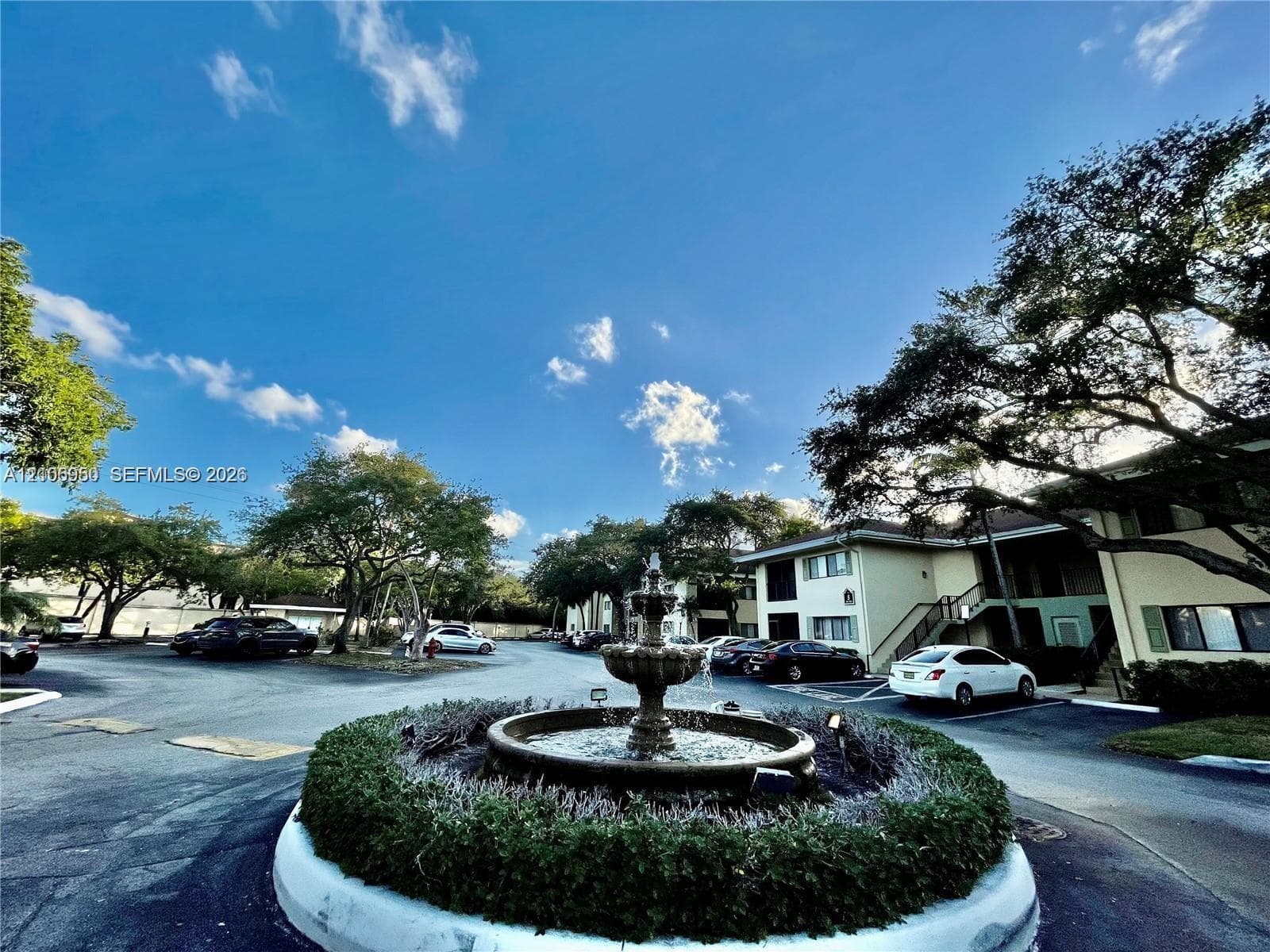 Central decorative water fountain featuring a tiered stone basin surrounded by manicured landscaping and mature trees