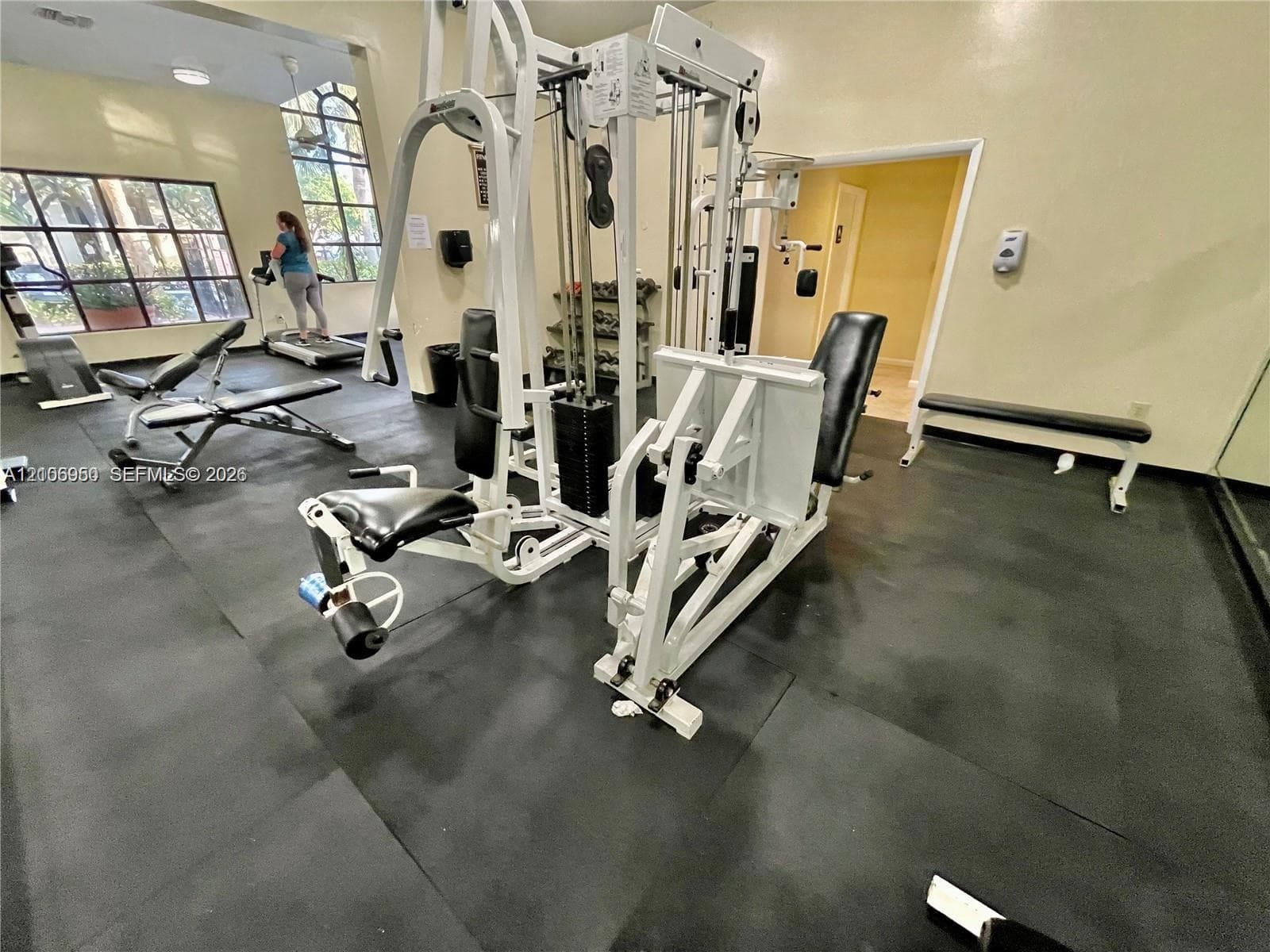 Fitness area featuring rubber flooring, large multi-pane windows, and high ceilings