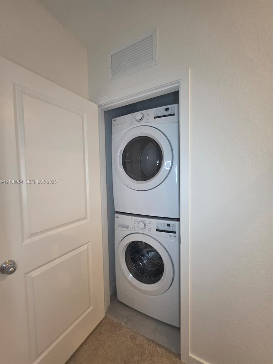 Laundry closet featuring a white stacked washer and dryer unit and a paneled interior door