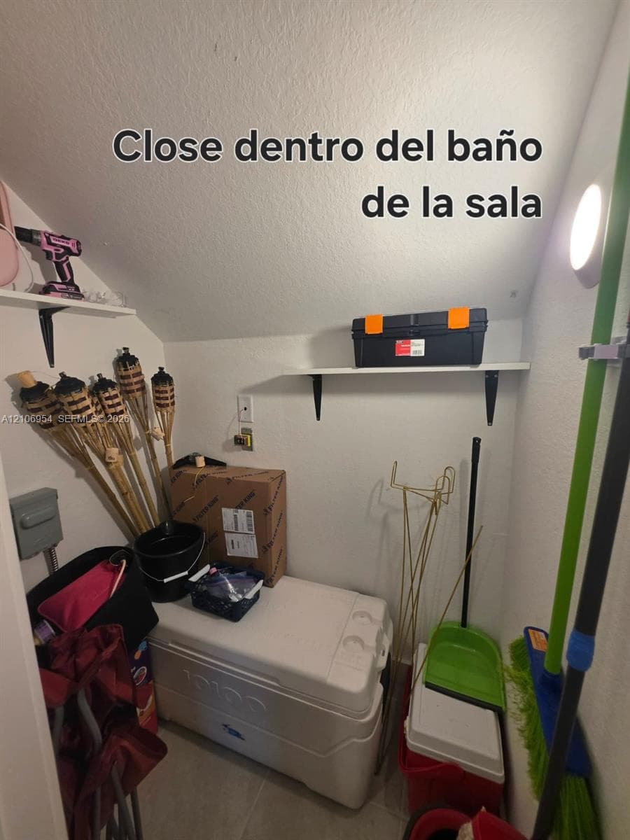 Storage closet featuring two wall-mounted shelving units and an integrated electrical outlet