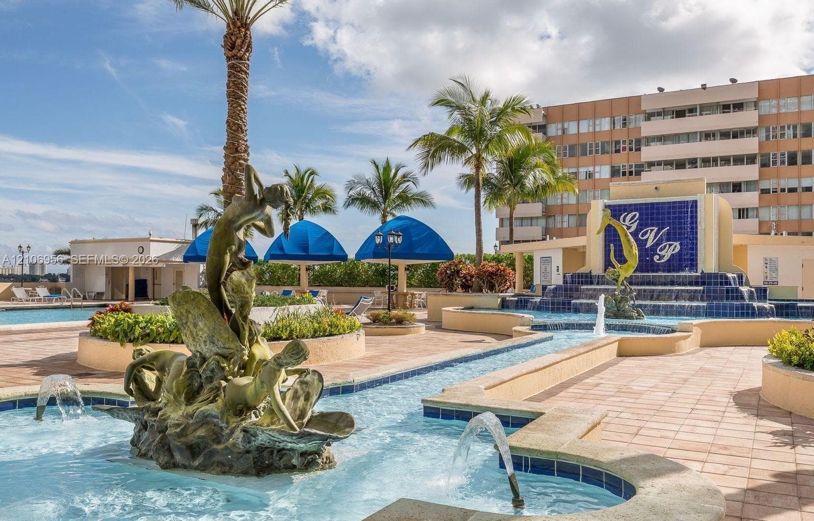 Outdoor pool deck featuring decorative bronze water fountains, stone-tile flooring, and built-in masonry planters
