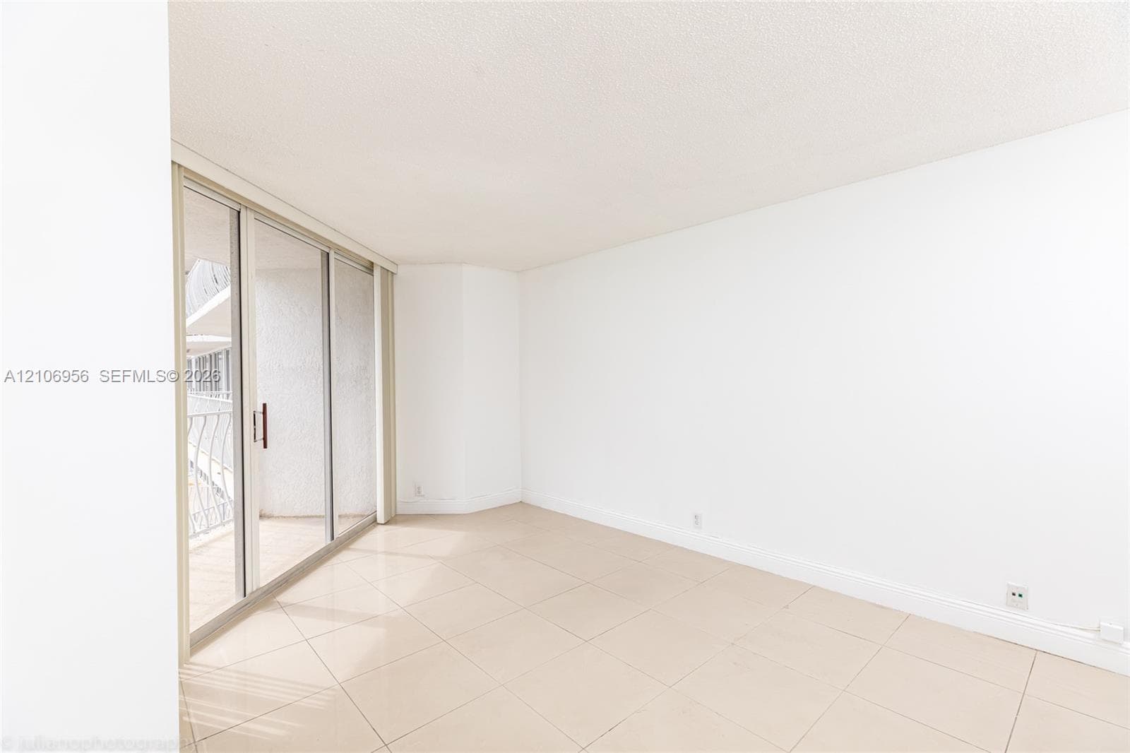 Large-format tile flooring, oversized sliding glass doors, and an attached balcony with decorative metal railing