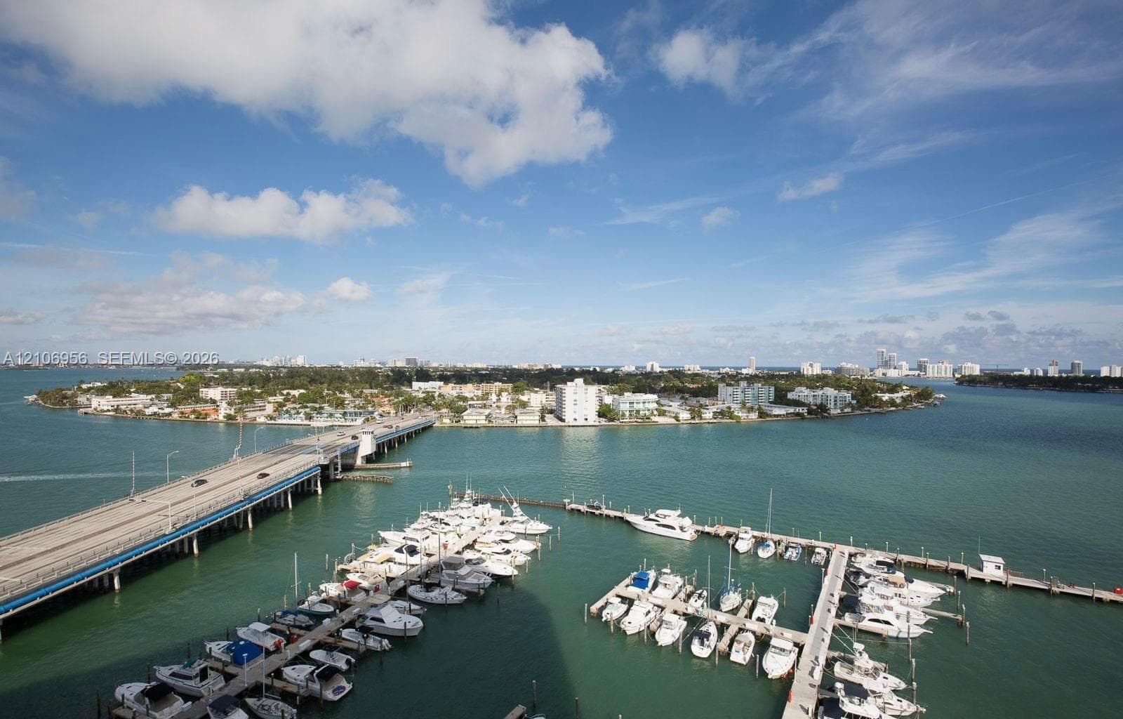 Elevated waterfront perspective featuring a multi-slip marina, concrete bridge infrastructure, expansive bay water, and coastal landscape