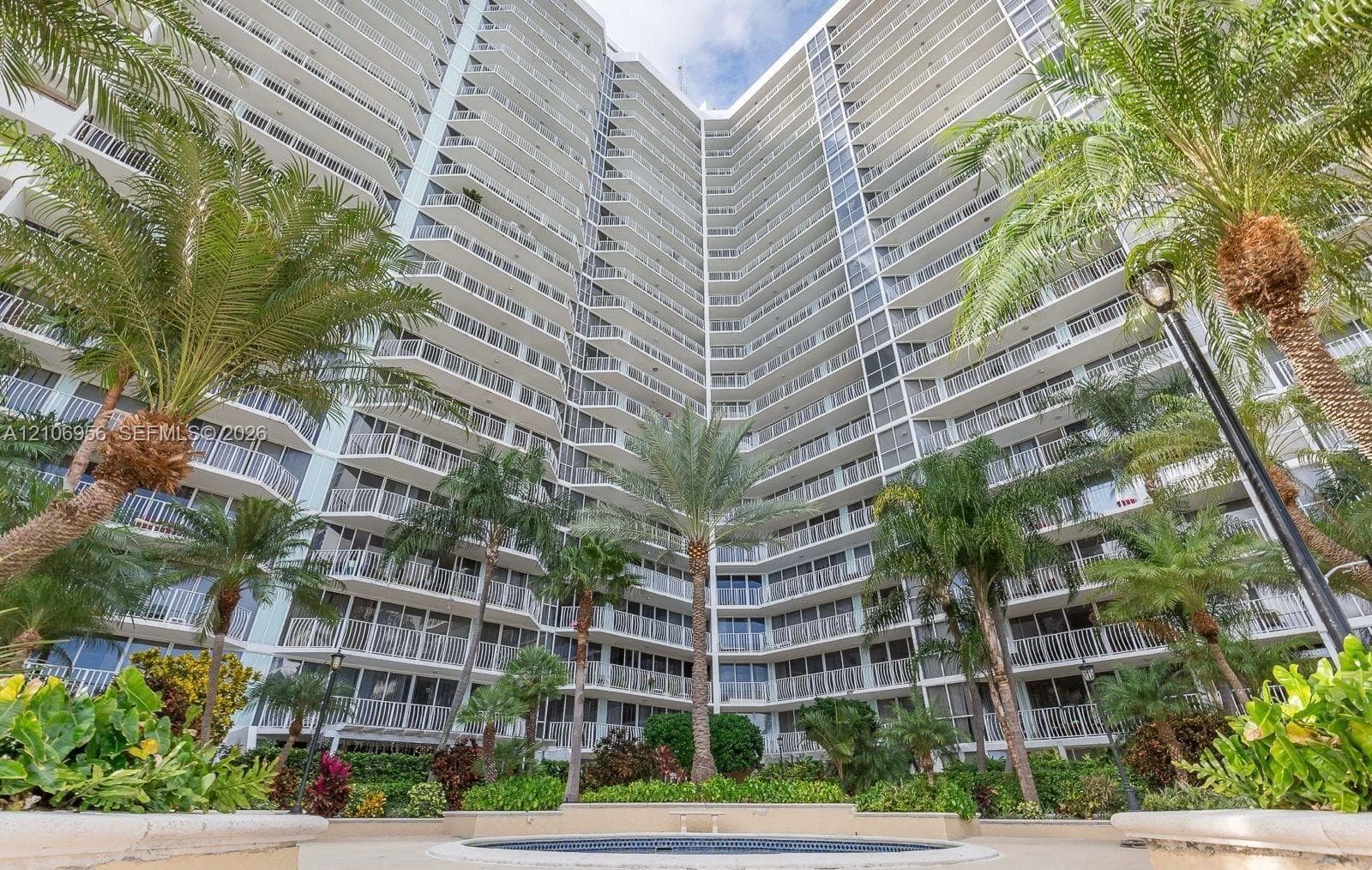 High-rise residential exterior featuring stacked private balconies, metal railing systems, central landscaped courtyard, and mature palm trees