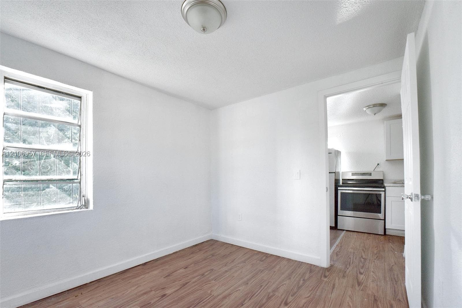 Interior room featuring wood-finish flooring, a multi-pane window, and a flush-mount ceiling light fixture