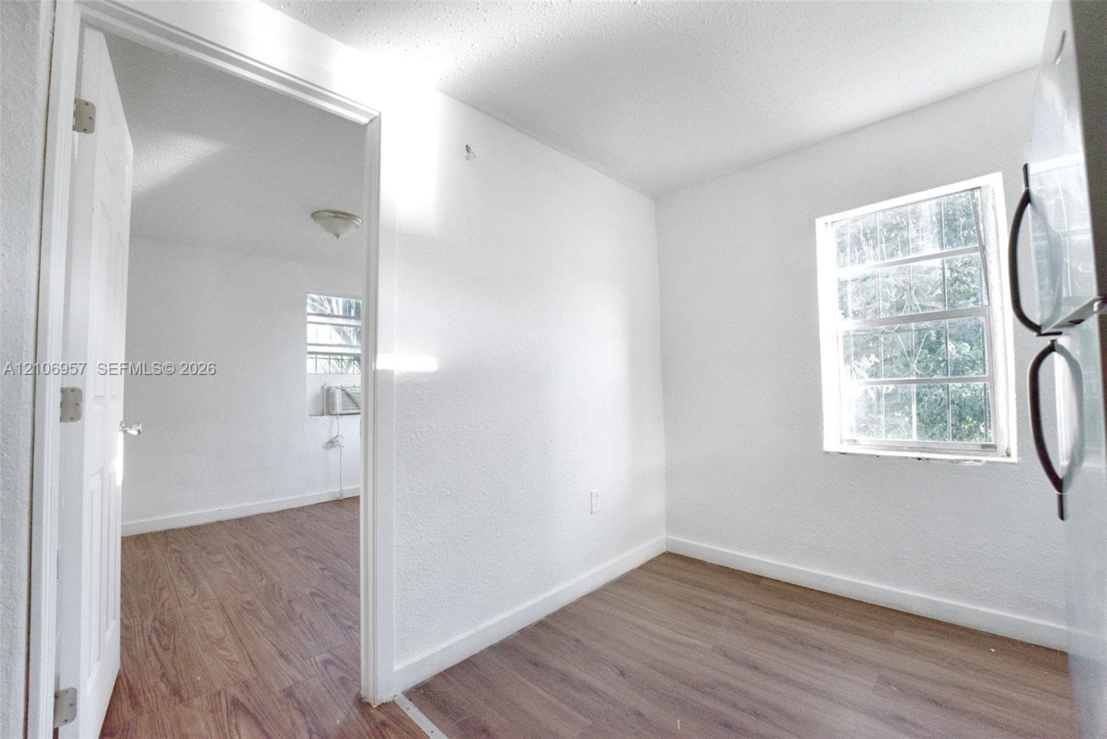 Interior space featuring wood-finish flooring, white walls, and multiple windows providing natural light