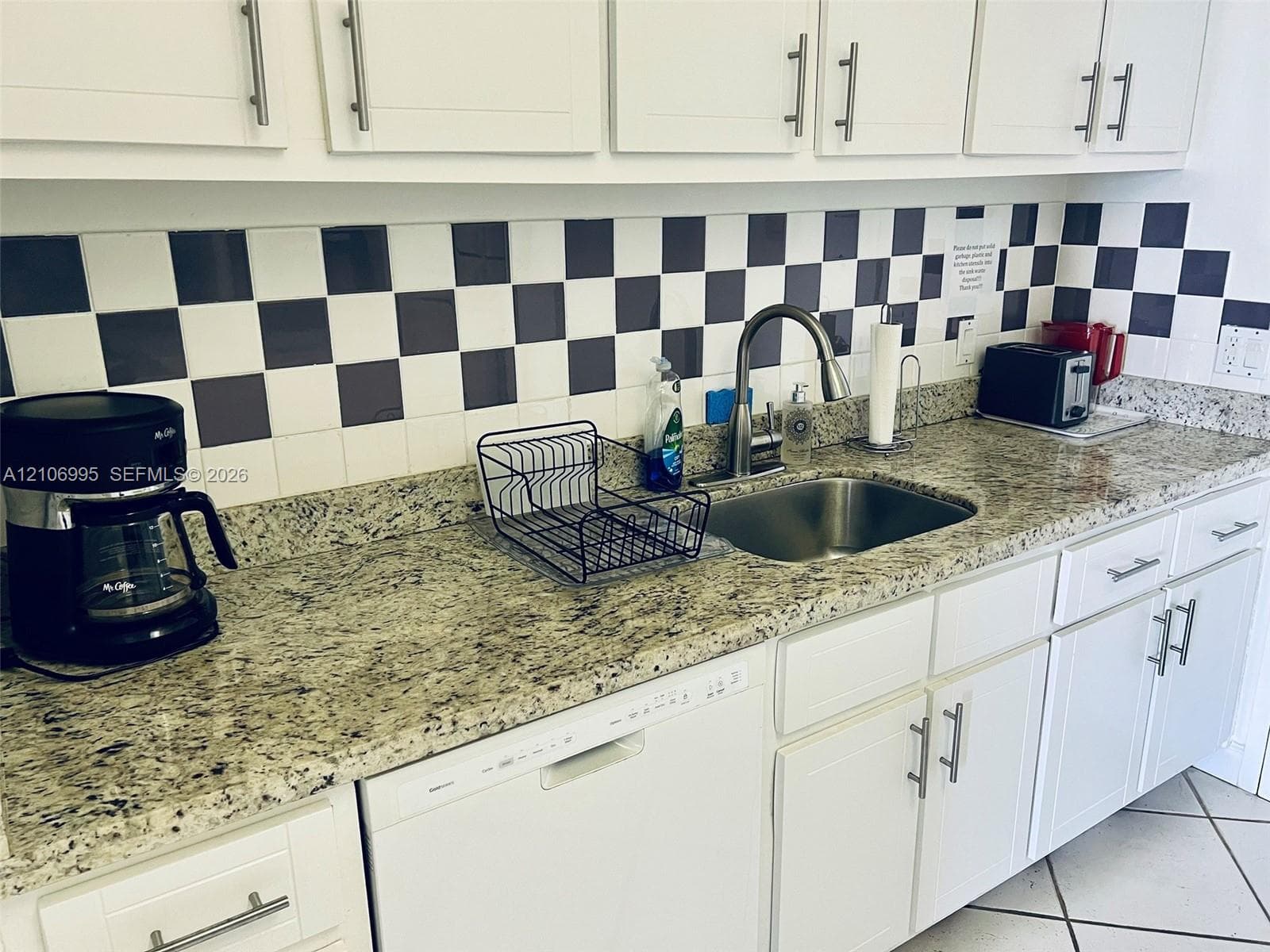 Kitchen featuring stone countertops, shaker-style white cabinetry with brushed-metal pulls, a stainless steel undermount sink, and a high-arch pull-down faucet