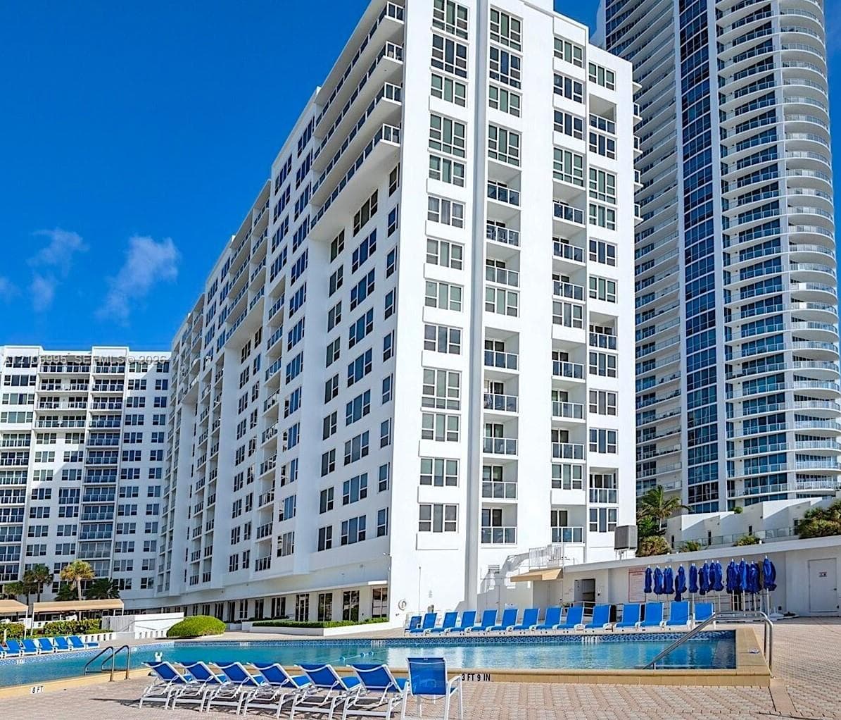High-rise exterior featuring private balconies and a ground-level swimming pool with paver decking