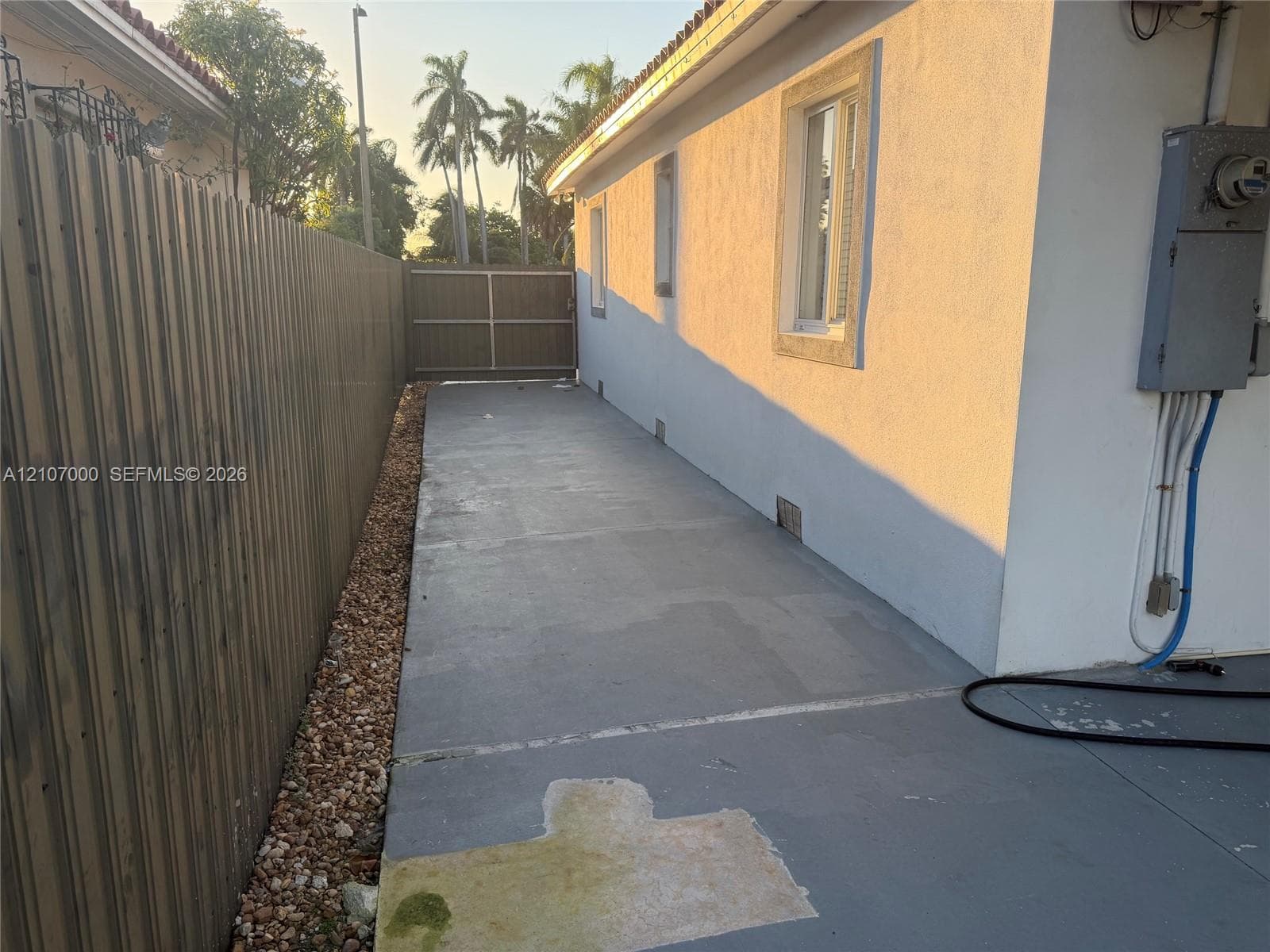 Exterior side yard featuring a concrete pathway, privacy fencing, and a gated entrance